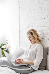 Authentic Pricing woman leaning against wall with laptop